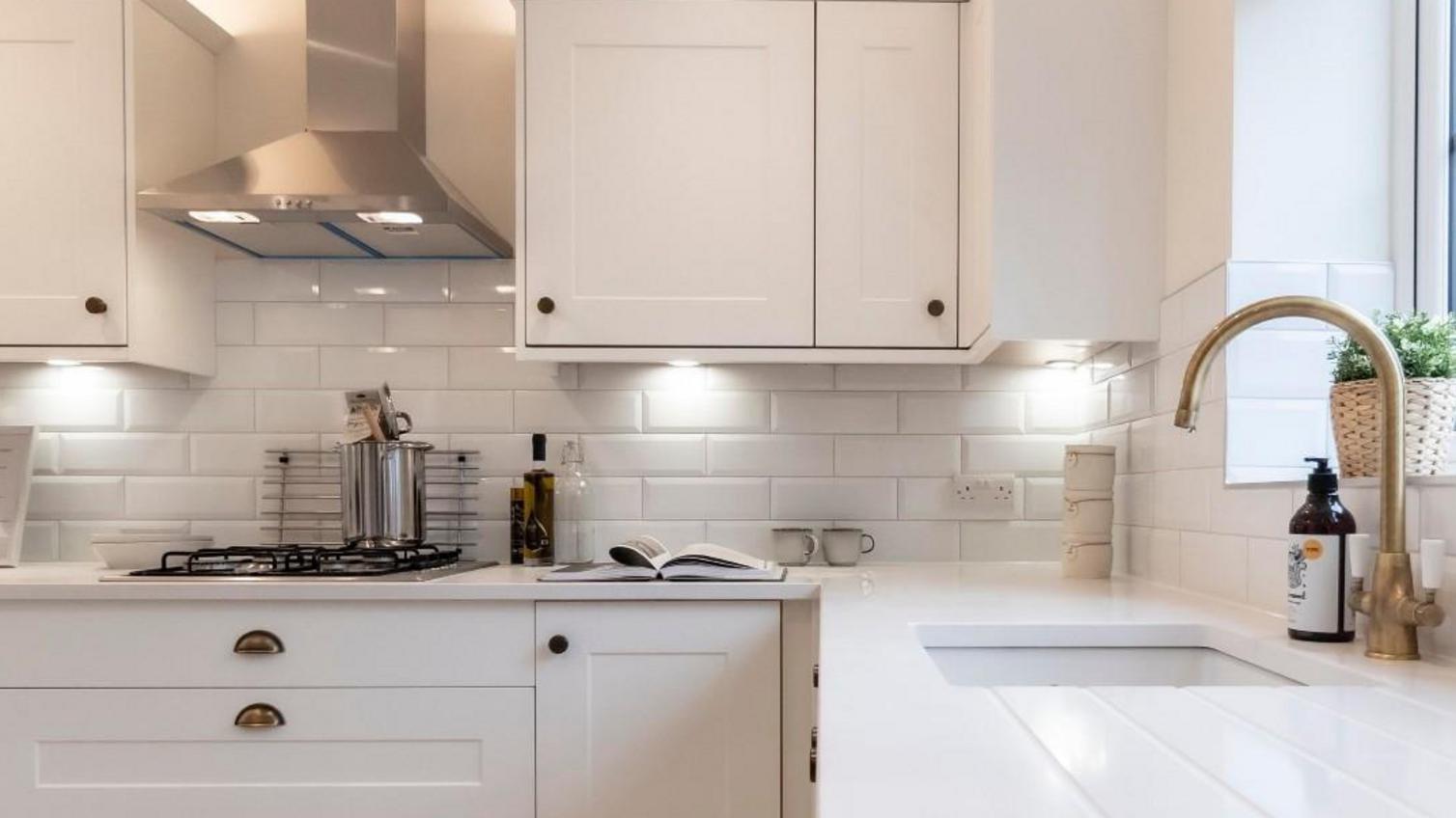 Bespoke worktop idea using white worktops, white shaker cupboards, and aged-brass cup and knob handles.