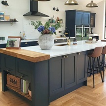 Navy shaker kitchen design with island, quartz and solid wood worktop, and brass cup and knob handles.