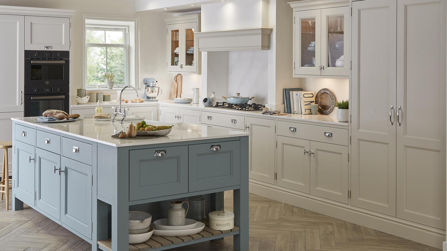 A shaker island kitchen in a large, open room, in a two tone, blue and white style