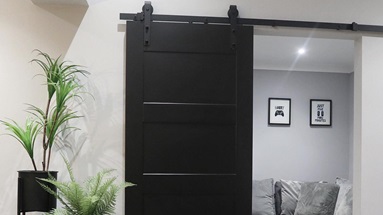 Compact living room idea using a black, panelled sliding door. Includes a light-grey tiled floor and oak dining furniture.