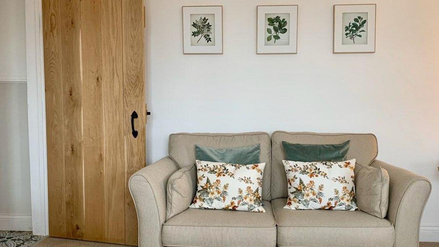 Traditional living room idea with a solid oak internal door, black hardware, a beige sofa, and floral cushions and artwork.