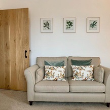Traditional living room idea with a solid oak internal door, black hardware, a beige sofa, and floral cushions and artwork.