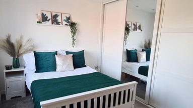 A room containing a green bed and a set of sliding wardrobe doors