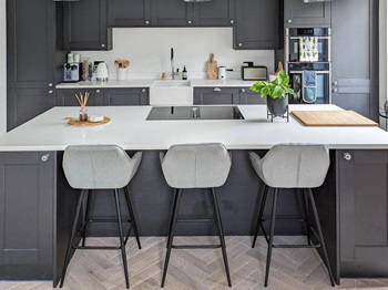 Shaker kitchen island idea with dark-grey units, white worktops, and a black induction hob for a sleek look.