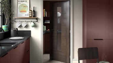 A glazed walnut internal door inside a bold red and black kitchen.