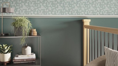 A green hallway with a timber handrail, black spindles, and a painted dado rail.