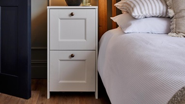 A bedside table with two white Bridgemere drawer fronts. It has brass round handles that match the navy door's handles.