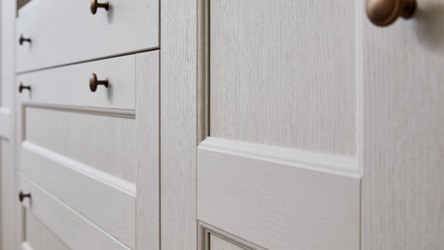 Tall wardrobes with Bridgemere door and drawer fronts. They have a white, porcelain tone and a grained wood finish.