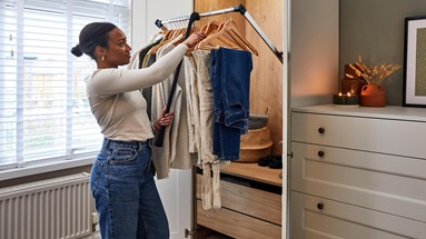 Jade using the internal pull-down rail inside the white shaker wardrobes. Clothes are hung on hangers and has an oak interior