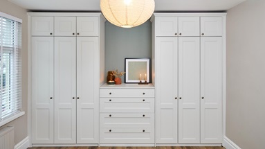 Two sets of tall, three-door wardrobes and matching drawers. They have a porcelain, white colour and grained finish.