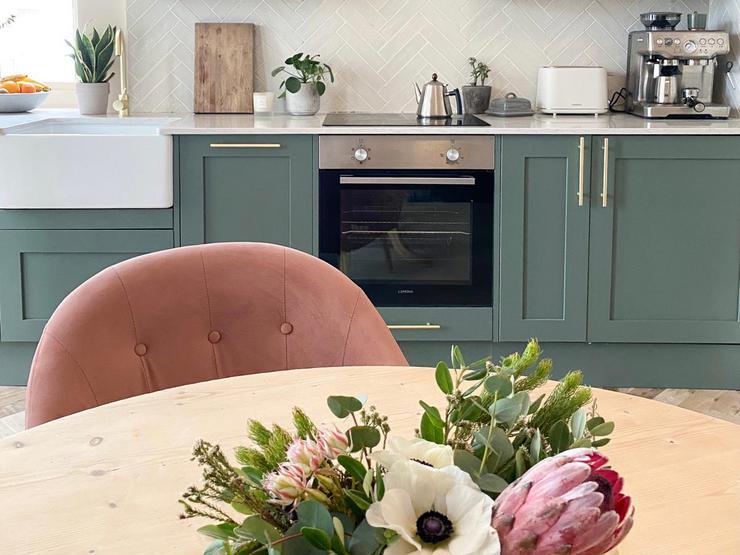 Teal paintable kitchen idea with shaker cupboards, brass handgrips, white tiles, quartz counters, and a white marble table.