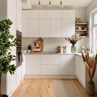 A small white kitchen makeover using matt handleless cupboards, white quartz worktops and wood flooring.
