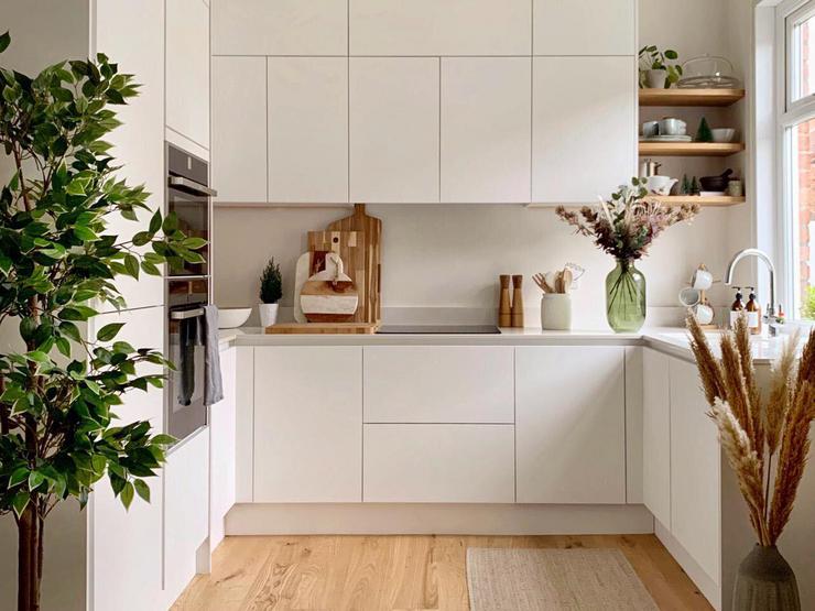A small white kitchen makeover using matt handleless cupboards, white quartz worktops and wood flooring.