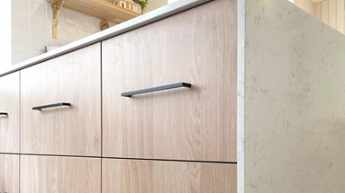 Bank of oak effect slab drawers with black handles