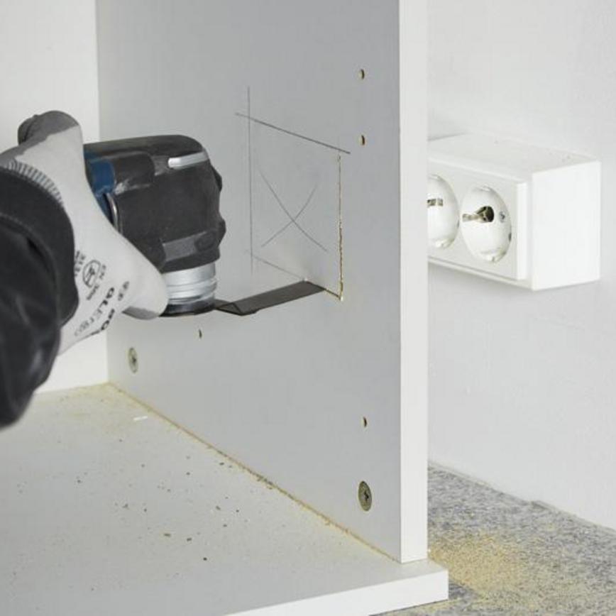 Multi tool blade set being used to cut a hole for electrics in a kitchen cabinet