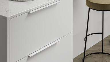 A simple white kitchen idea using slab cupboards and white matt bar handles. Contains a marble worktop for a luxurious feel.