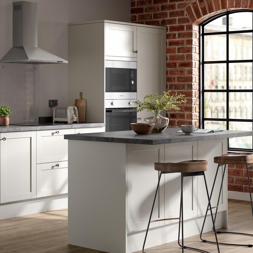 A shaker kitchen in a light white colour and single-wall layout. There are dark stone worktops and matching breakfast bar.