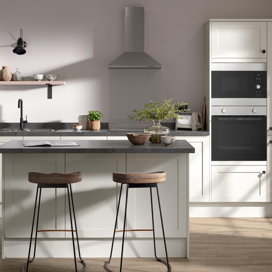 A shaker kitchen in a light white colour and single-wall layout. There are dark stone worktops and matching breakfast bar.