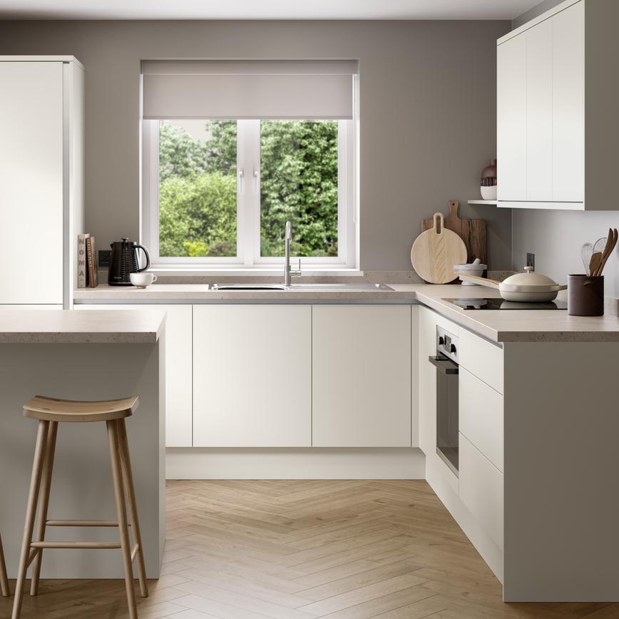 A white, porcelain kitchen with handleless fronts. It is in an l-shaped layout with a breakfast bar and oak-effect flooring.