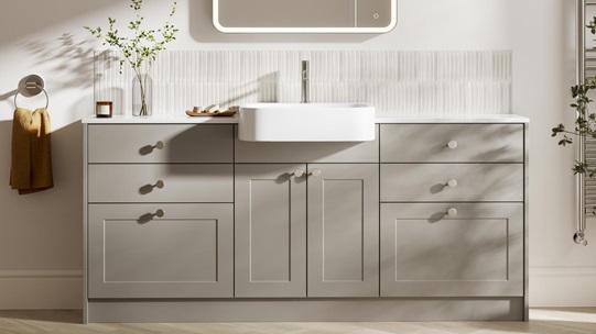Pale, pebble-toned bathroom door and drawer units in a shaker style. It has metallic knob handles, tap, and deep sink. 