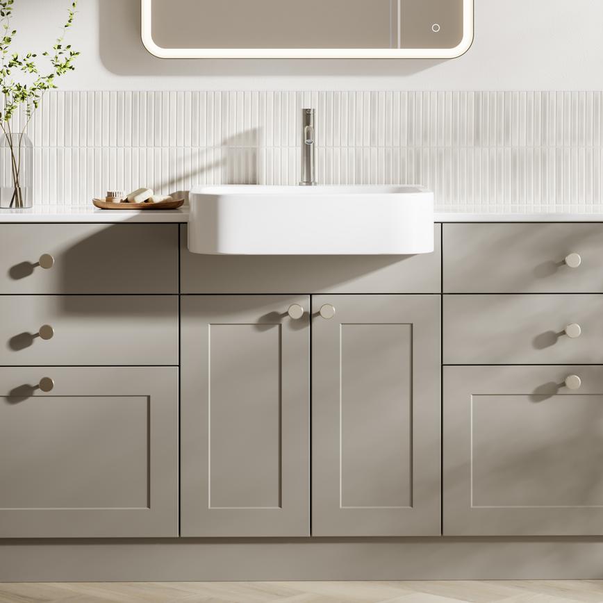 Pale, pebble-toned bathroom door and drawer units in a shaker style. It has metallic knob handles, tap, and deep sink.