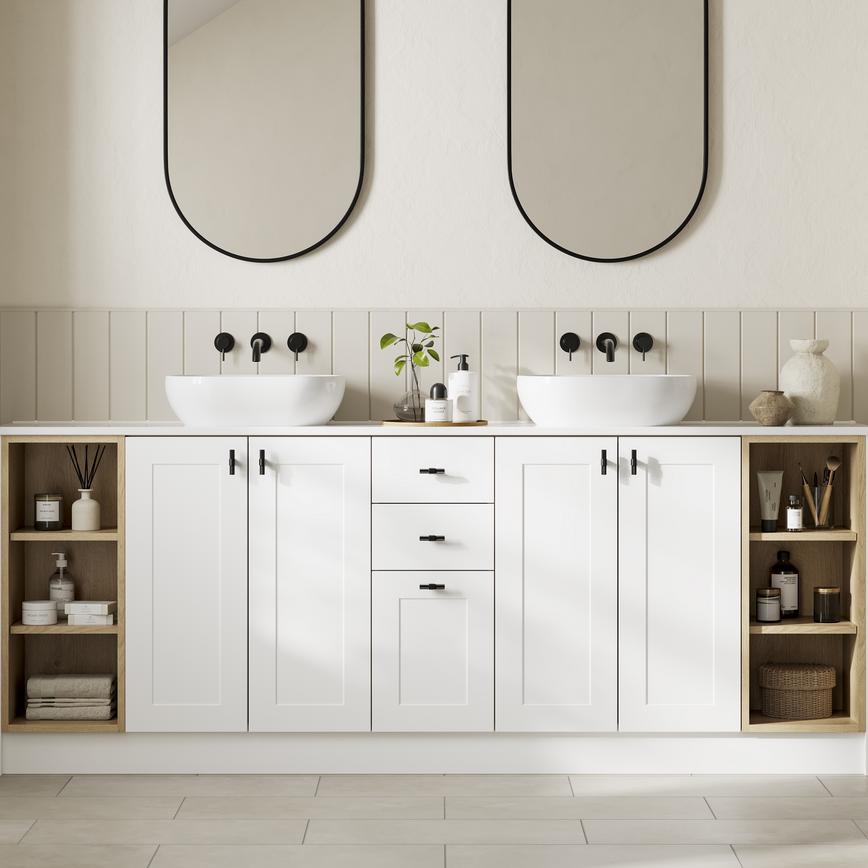 Bathroom with large, white shaker vanity units. It has black handle and tap accessories, with custom shelving to the side.