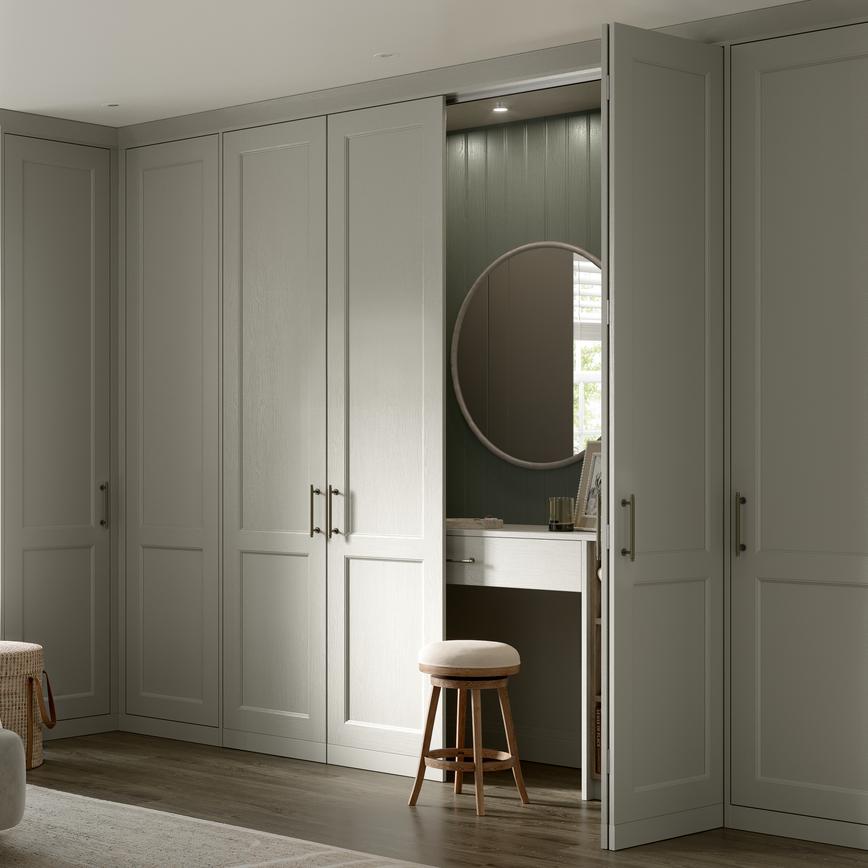 Bedroom with shaker-style fronts in a light pebble colour. Behind one door is a dresser unit with matching door and mirror.