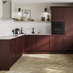 A garnet red shaker kitchen in an L-shaped layout. There are white worktops, oak laminate flooring and undermounted sink.