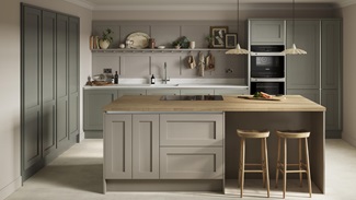 A green shaker kitchen with silver profiles for a handleless design. Has oak worktops and stone floors for a natural look.