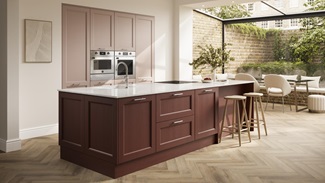 A two-tone, dark-red and light pink kitchen in an island layout. It has herringbone flooring and white worktops.