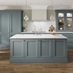 A blue shaker kitchen with in-frame doors in single wall and island layout. Finished with curved cabinets, white worktops.