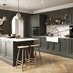 A dark-green kitchen with shaker doors in a single wall layout. It is styled with herringbone flooring and white worktops.