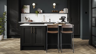 A charcoal black shaker kitchen in a single-wall layout, with island. There are white worktops and chevron oak flooring.