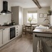 A rustic kitchen in a galley layout. Contains cream, shaker cupboards, dark-wood worktops, and a black, built-under oven.