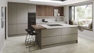 A sand grey kitchen in island layout with matching stone-effect floor tiles. There are also textured walnut wall cabinets.