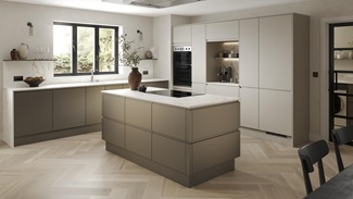 A handleless, bronze kitchen in an L-shaped, island layout. It has white worktops, chevron flooring, and an induction hob.