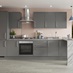 A modern grey kitchen in a l-shape layout with slab doors. Has a marble-effect breakfast bar, and a built-under oven.