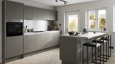 An l-shaped kitchen layout with green cabinets white marble-effect worktop, and pale wood flooring.