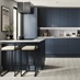 A marine blue kitchen with handleless cabinet doors. It is in a one-wall layout with a breakfast bar and grey oak flooring.