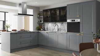 Blue kitchen with shaker doors in a l-shape layout. Contains marble worktops, black glass wall units, and aged brass handles.