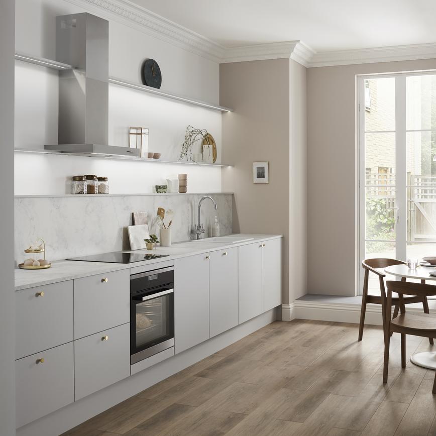 Single wall dove grey kitchen with copper knob handles, white grey marble kitchen worktop and built under oven.