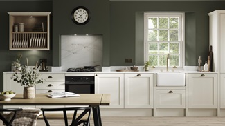 A cream, shaker kitchen in a single-wall layout. Features light oak flooring, ceramic sink, and brass tap and accessories.