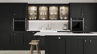 A charcoal shaker kitchen from Ilfracombe, in an island layout with breakfast bar. It has white counters and stone flooring.