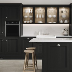 A charcoal shaker kitchen from Ilfracombe, in an island layout with breakfast bar. It has white counters and stone flooring.