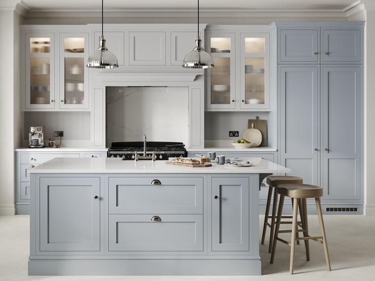 A mist blue, shaker Ilfracombe kitchen in an island layout. It has stone-effect flooring, marble effect breakfast bar. 