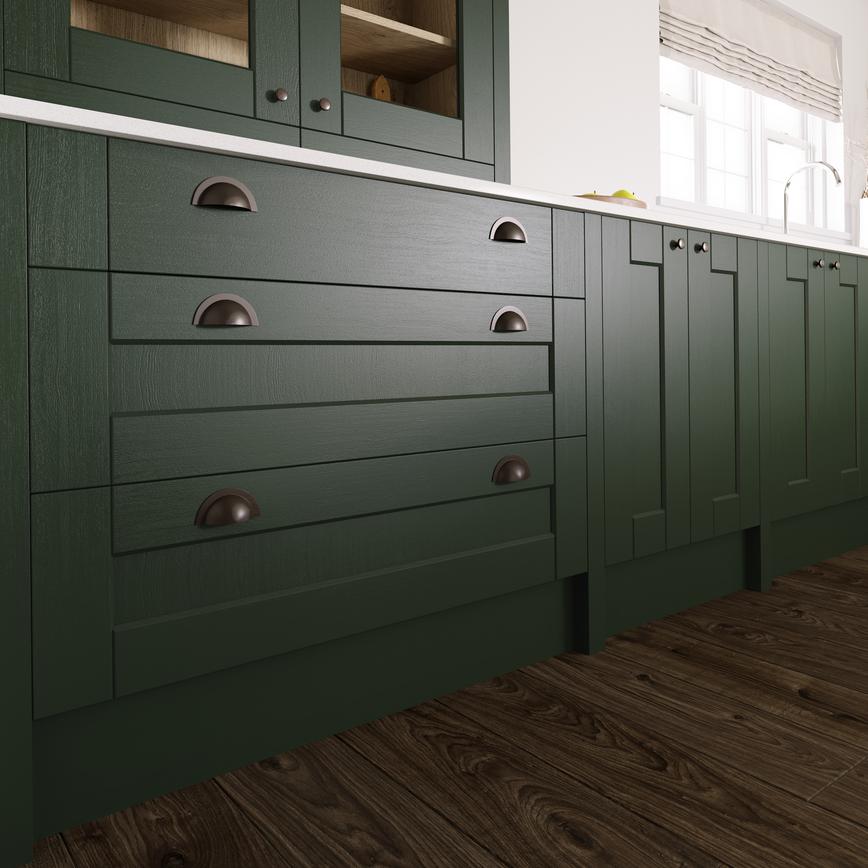 Dark-green kitchen base units, with shaker style cupboards and drawers. Showing pewter cup handles and a thin white worktop.