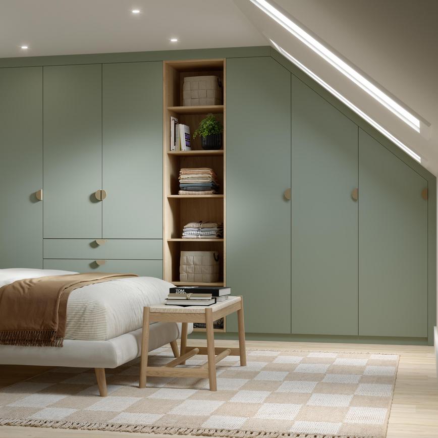 A modern bedroom with matt, reed green wardrobe doors and drawers. Behind the bed is dark wood panels and oak flooring.