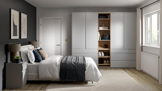 A matt dove grey bedroom with tall wardrobes and matching drawers. It has shelves in between and light, oak-style flooring.