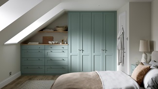 A Halesworth bedroom with seafoam blue wardrobes & drawers. It also has wood-effect flooring, and oak counters & shelving.
