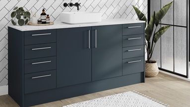 Nautical bathroom idea with marine-blue slab cupboard doors and white worktops. Includes silver bar handles and oak flooring.